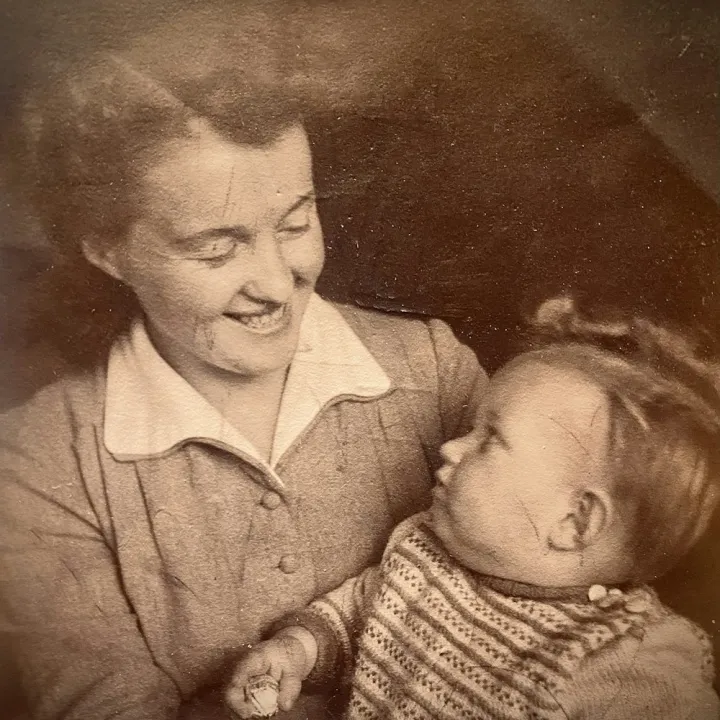 An old sepia photograph of a woman smiling at a baby
