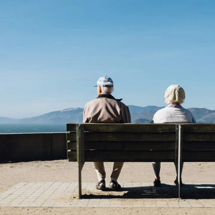 A couple sitting on a bench looking out to sea