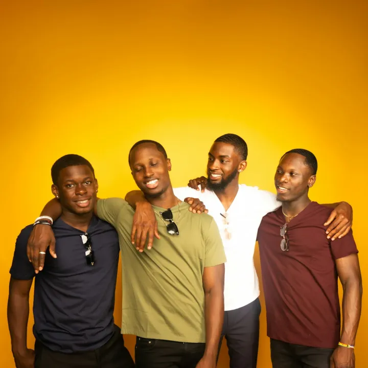 Four friends standing together smiling
